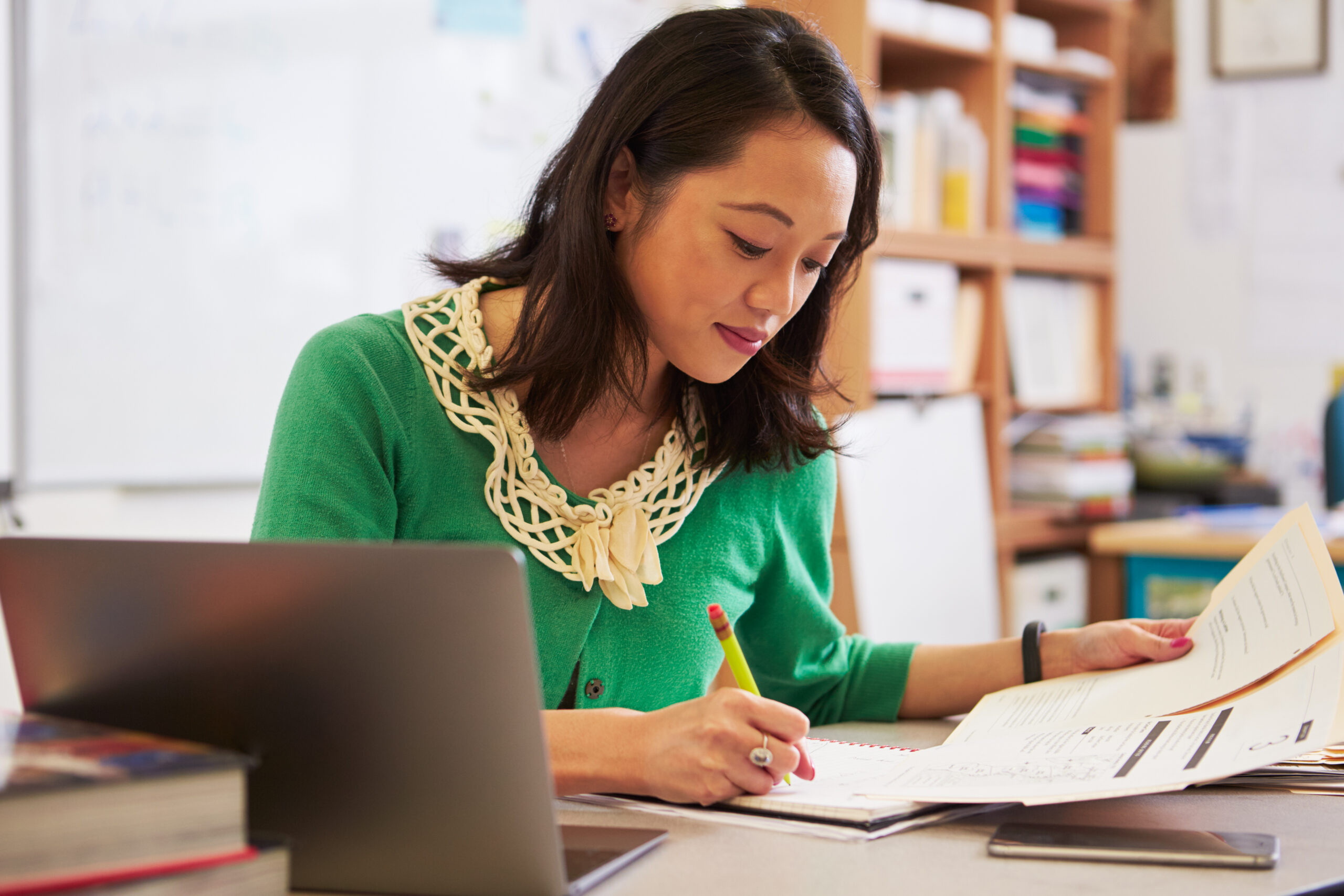 Teacher working at desk with laptop.